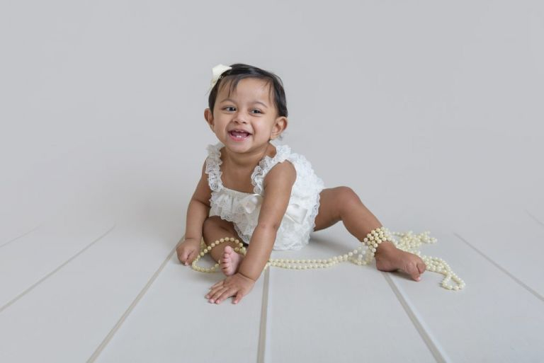 first birthday photoshoot kent. Baby girl in frilly romper