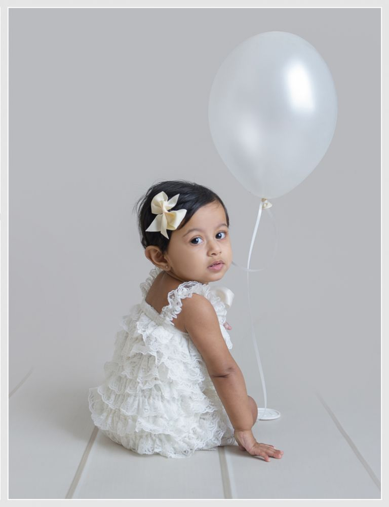 Baby girl in frilly romper for first birthday photography